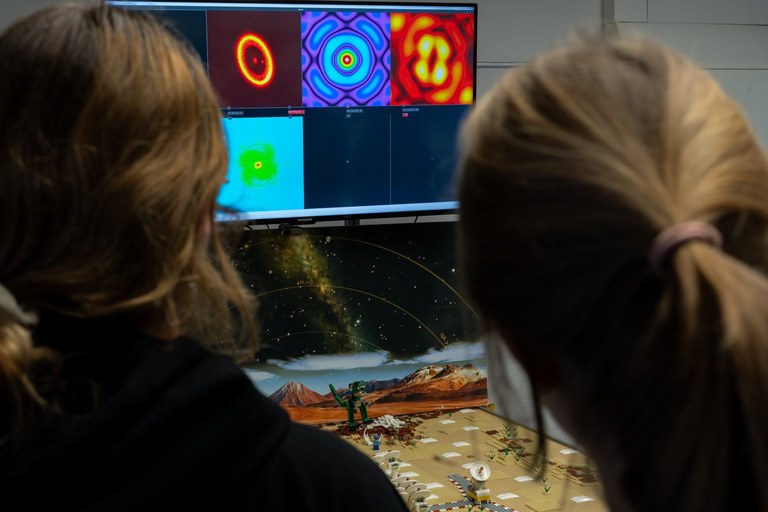 Im Astronomie-Workshop bestaunten die jungen Frauen den Lego-Nachbau des ALMA Observatoriums. Auf den Bildschirmen sind jeweils das Originalbild des Objekts sowie das durch Lego-ALMA beobachtete Bild zu sehen.