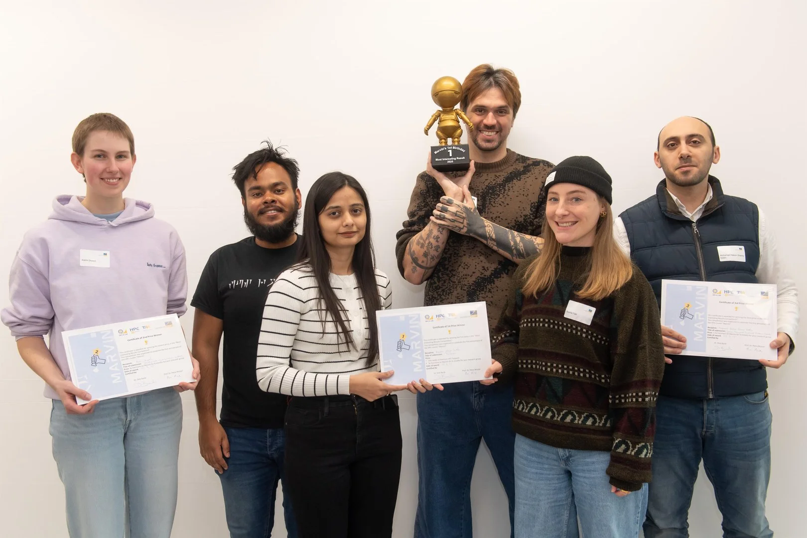 The first, second and third places went to a wide variety of innovative projects. - The winners of the competition for the most exciting projects realized with Marvin last year (from left): Katrin Drysch took second place with “Development of magnesium batteries”. Aniket Sen, Shiza Fatimah, Nicolas Kluge Correa and Sophia Falk, who entered the race with “Tucano: Advancing Neural Text Generation for Portuguese”, were delighted to take first place. Mohamad Hakam Shams Eddin was delighted with third place for “Identifying Spatio-Temporal Drivers of Extreme Events.”