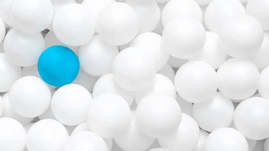 Eine Wissenschaftlerin und ein Wissenschaftler arbeiten hinter einer Glasfassade und mischen Chemikalien mit Großgeräten.